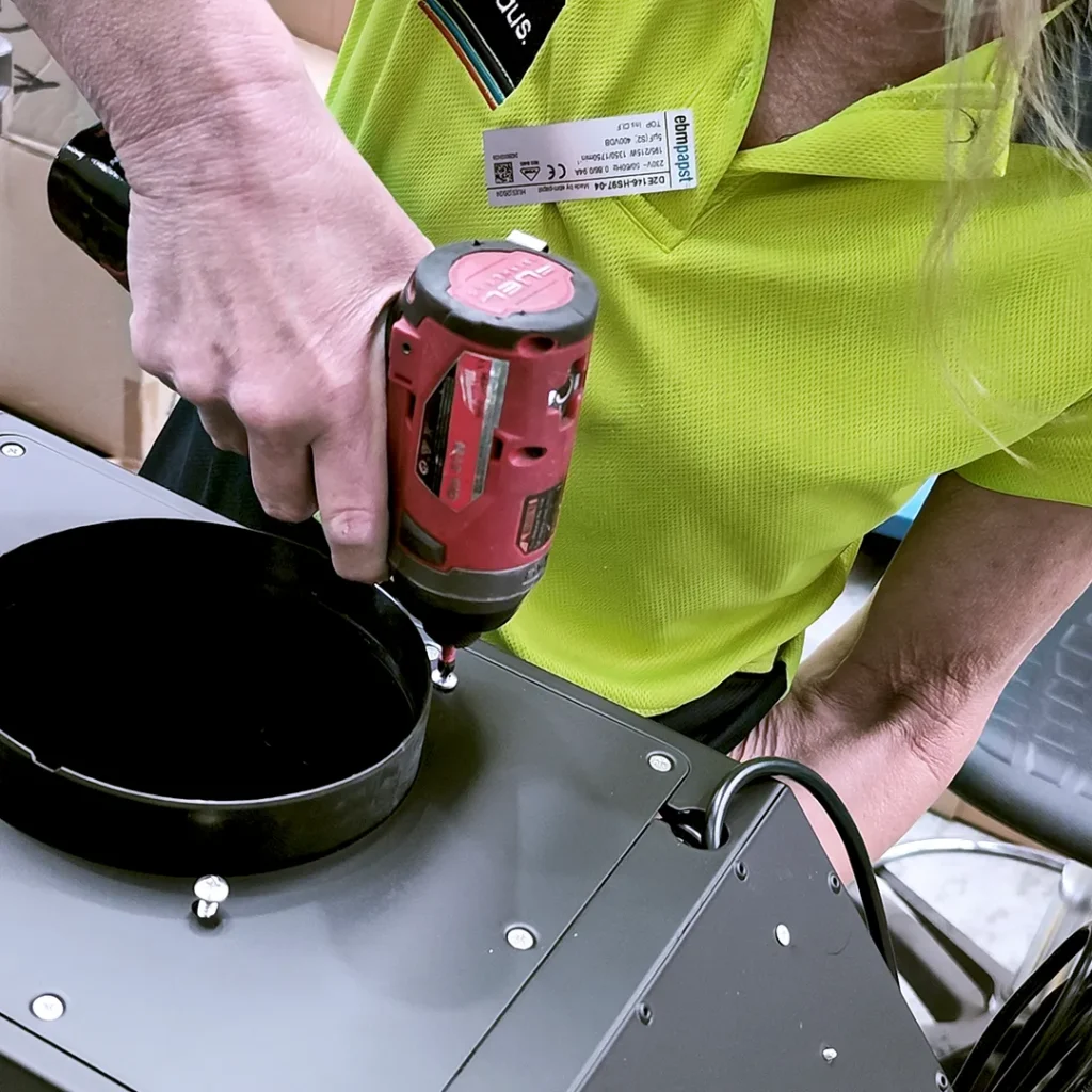 Close up shot of a production staff assembling a Whispair rangehood with a hand drill