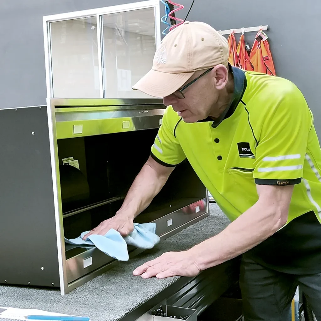 Production staff cleaning and polishing the surface of a rangehood on the assembly station
