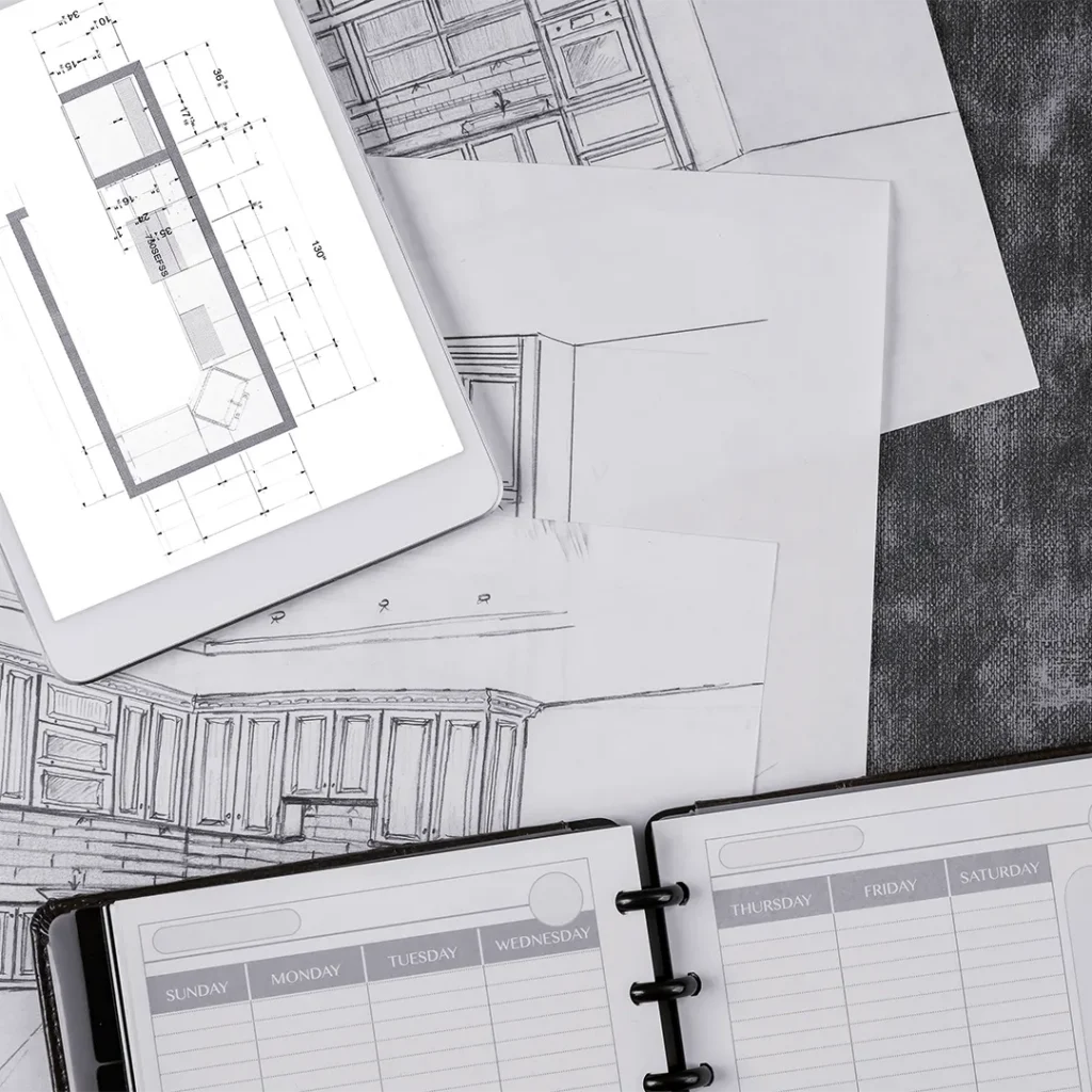 A table with scattered architect documents, diary and tablet