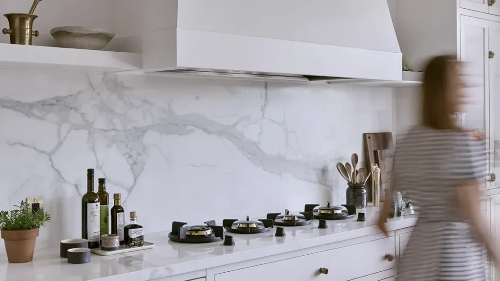 Lifestyle image featuring a White themed Kitchen with lady walking in motion with PITT Cooking Danau 4 Burner
